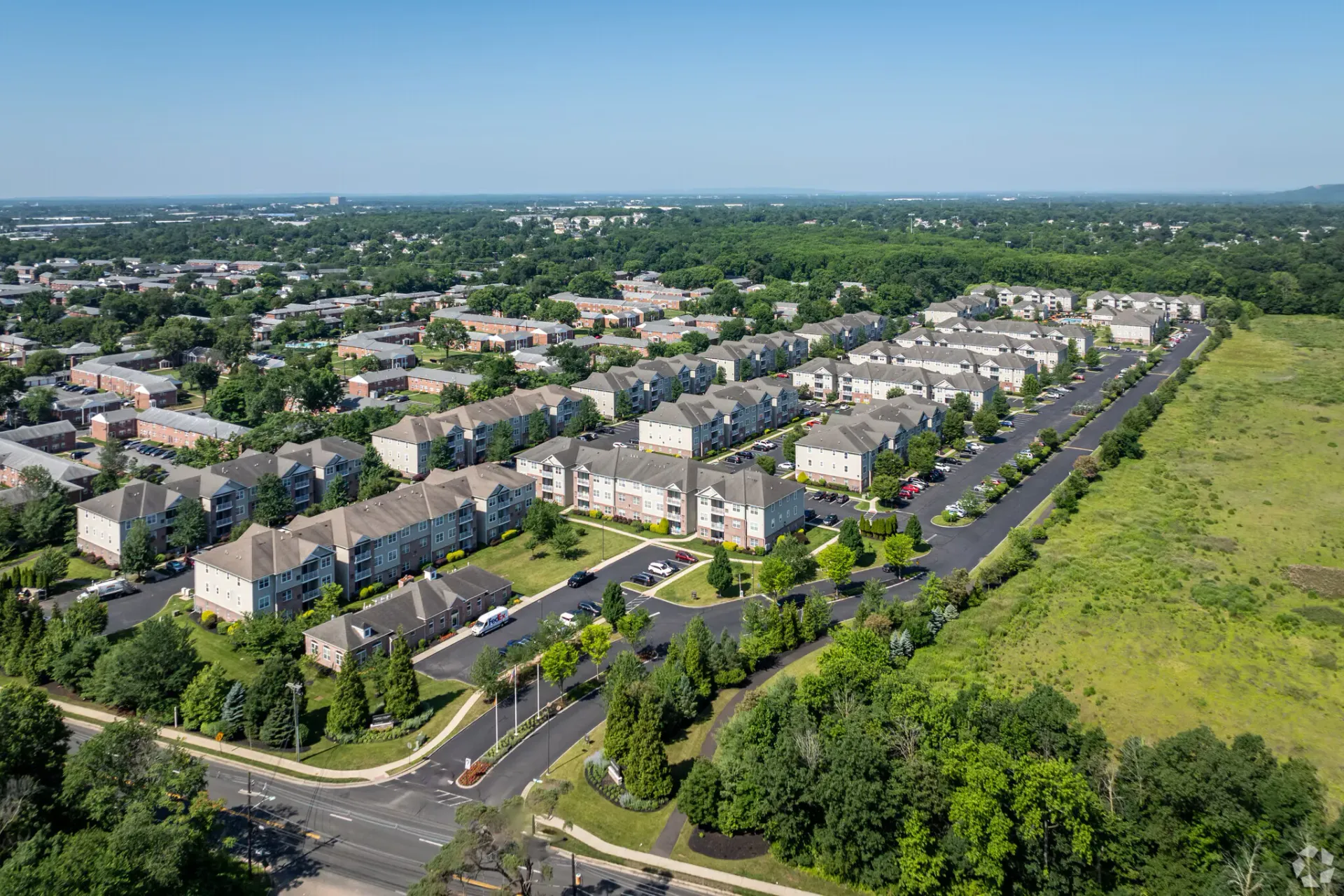 Aerial view of a large apartment community with multiple beige buildings, roads, and green landscaping.