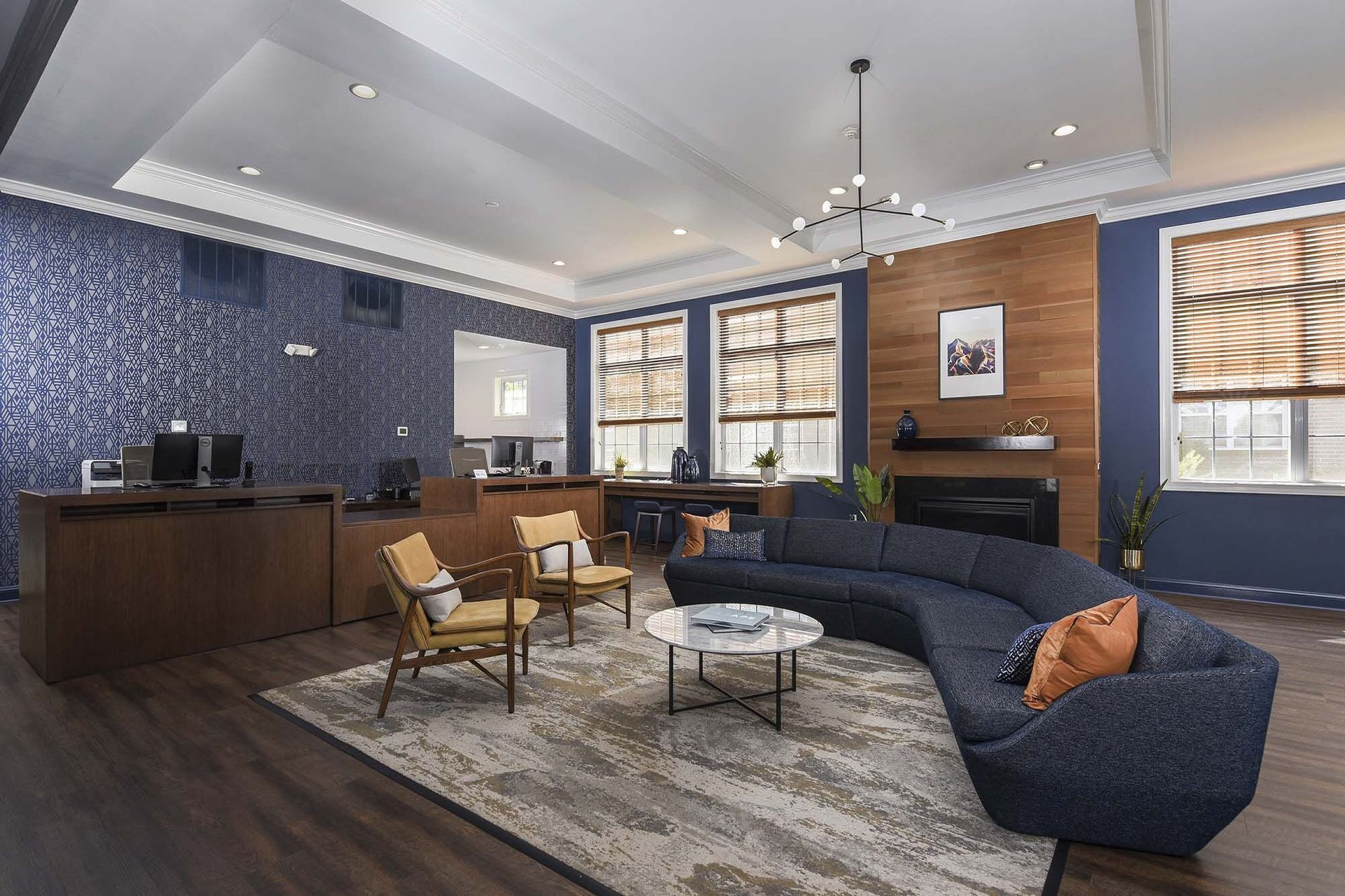 Modern apartment lobby with blue accent wall, seating, and a fireplace.