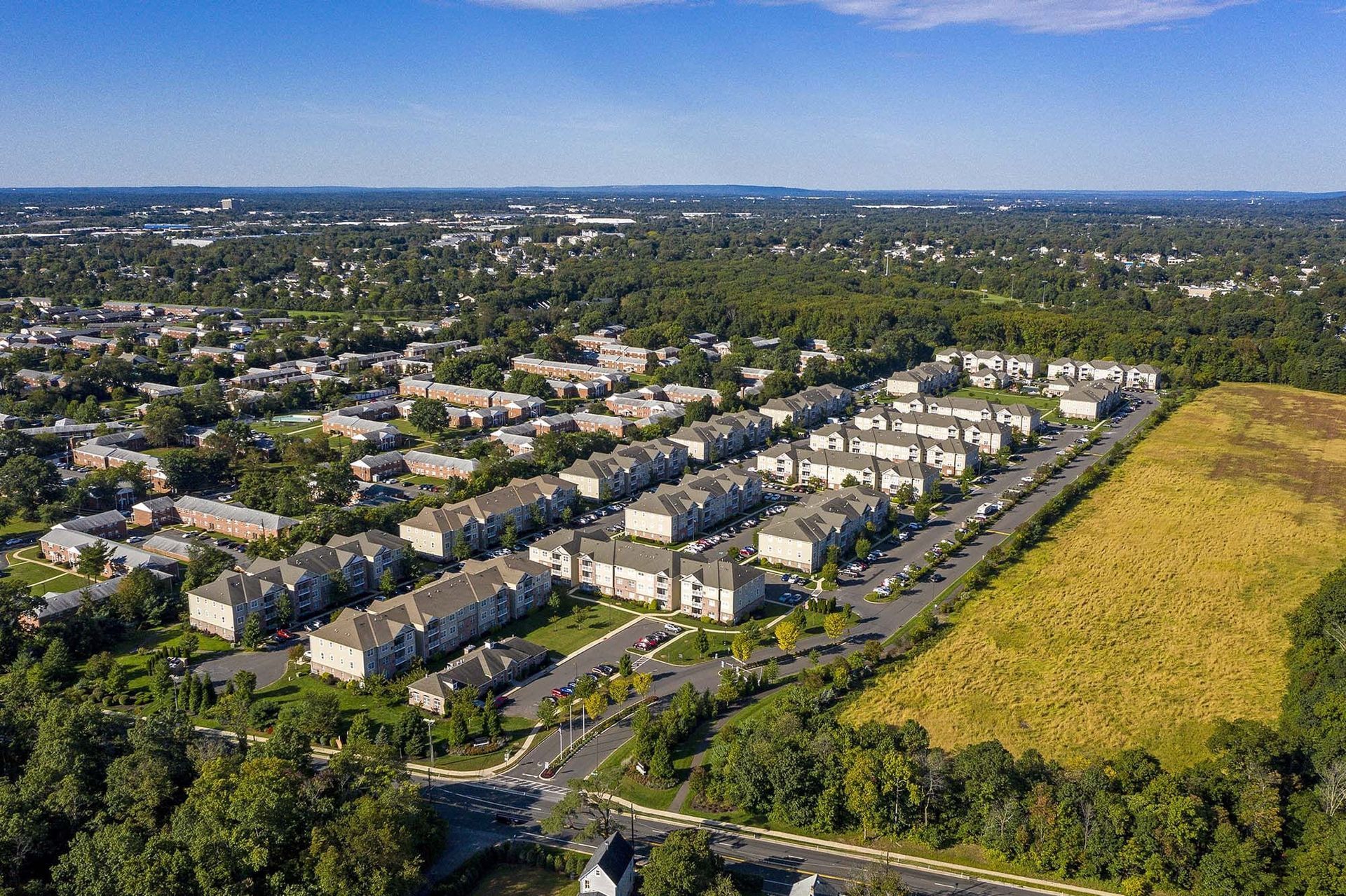 Aerial view of a large apartment community with rows of buildings, roads, and green spaces.