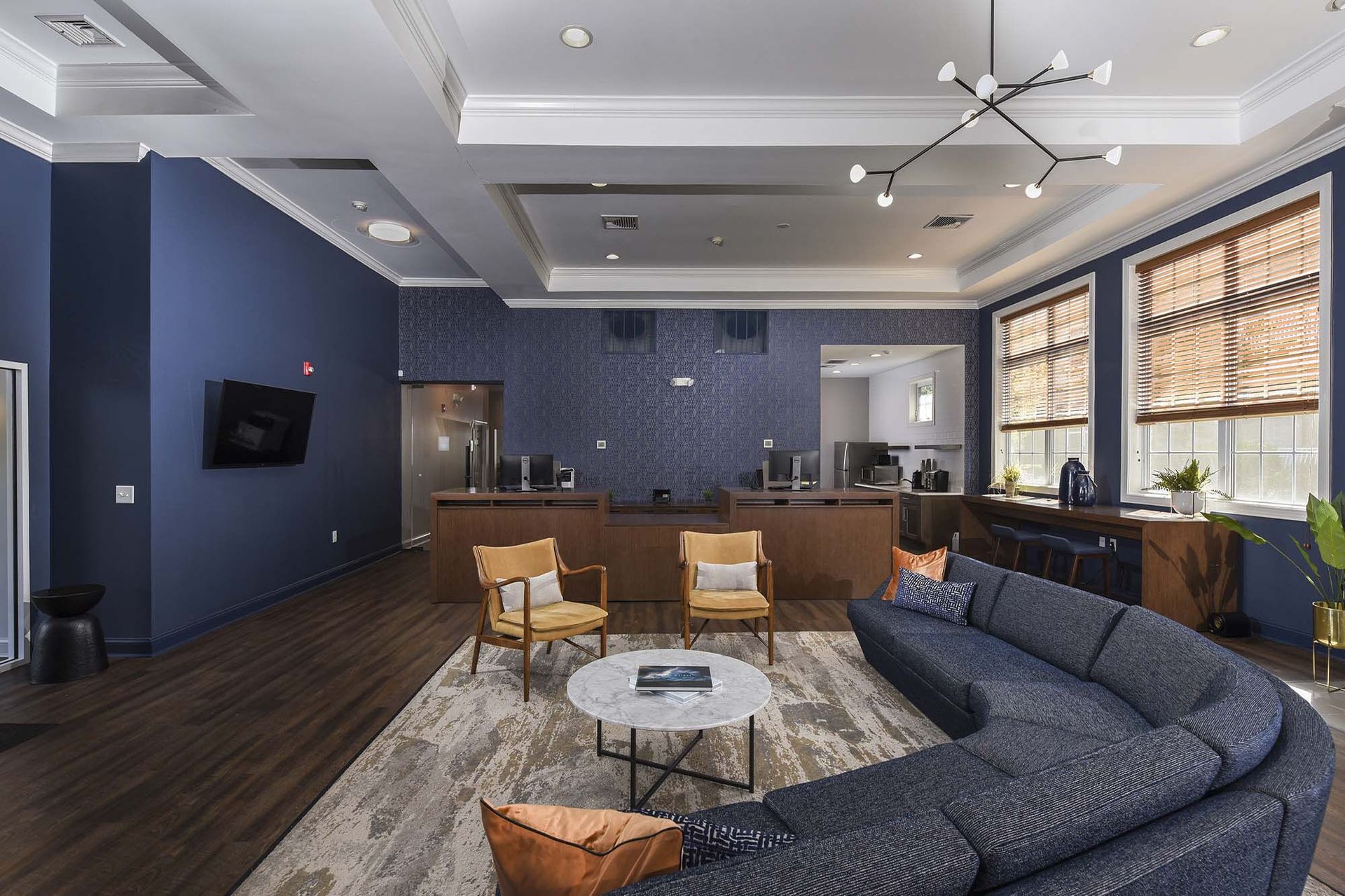 Interior community lounge with blue walls, modern seating, and a desk area with computers.