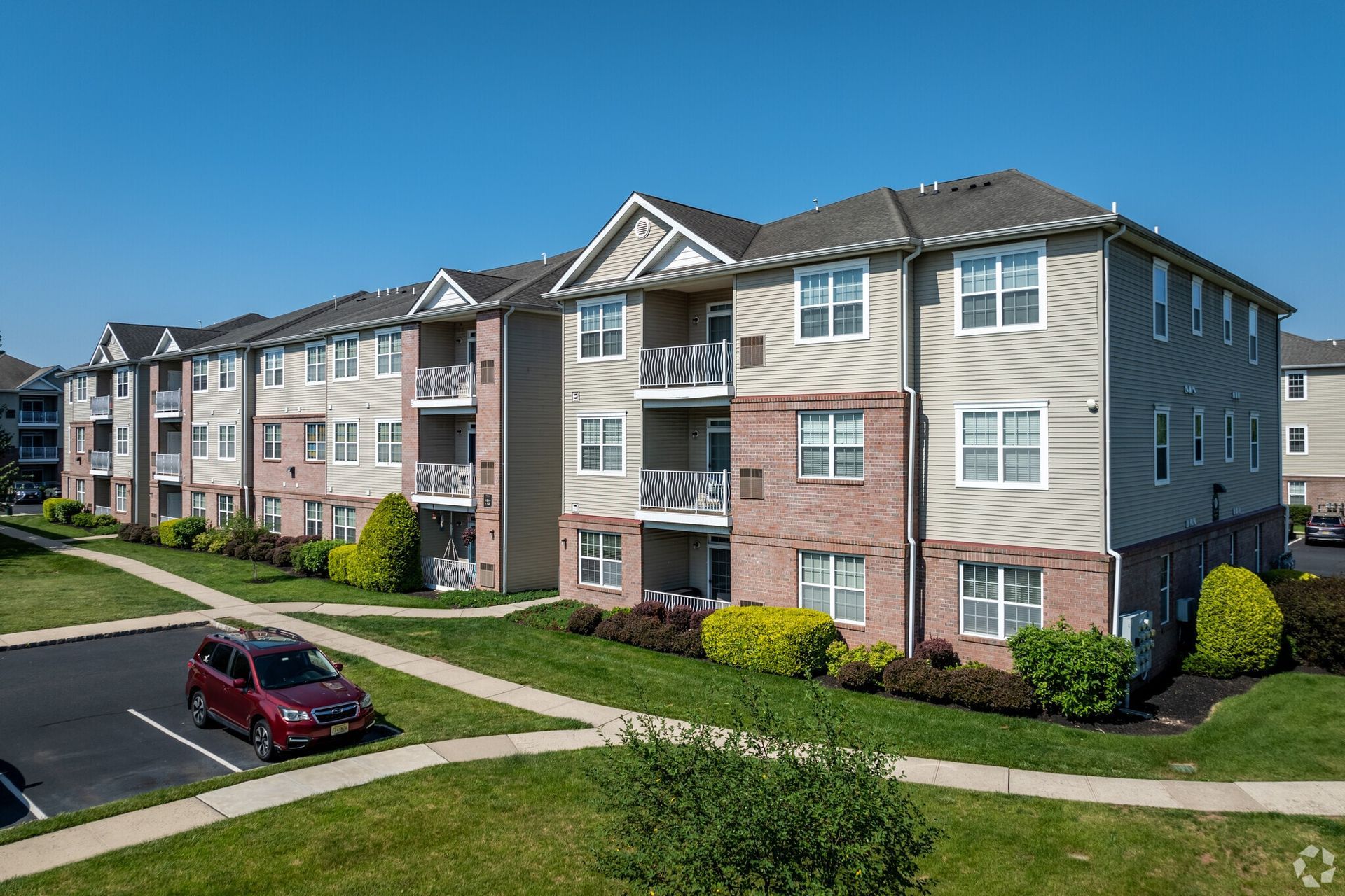Exterior view of a multi-building apartment complex with balconies under a blue sky.