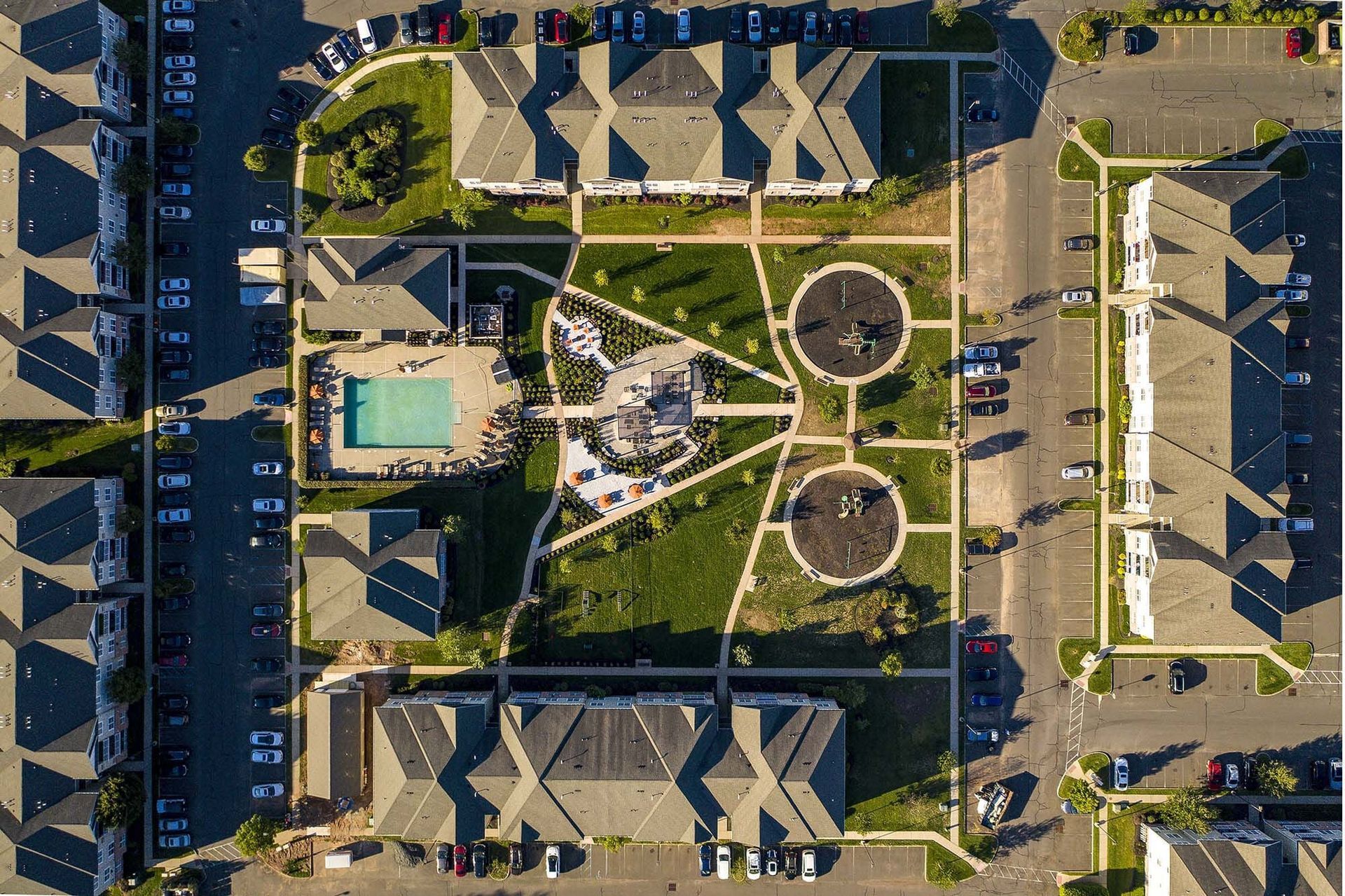 Aerial view of a multi-building apartment complex courtyard with a pool.