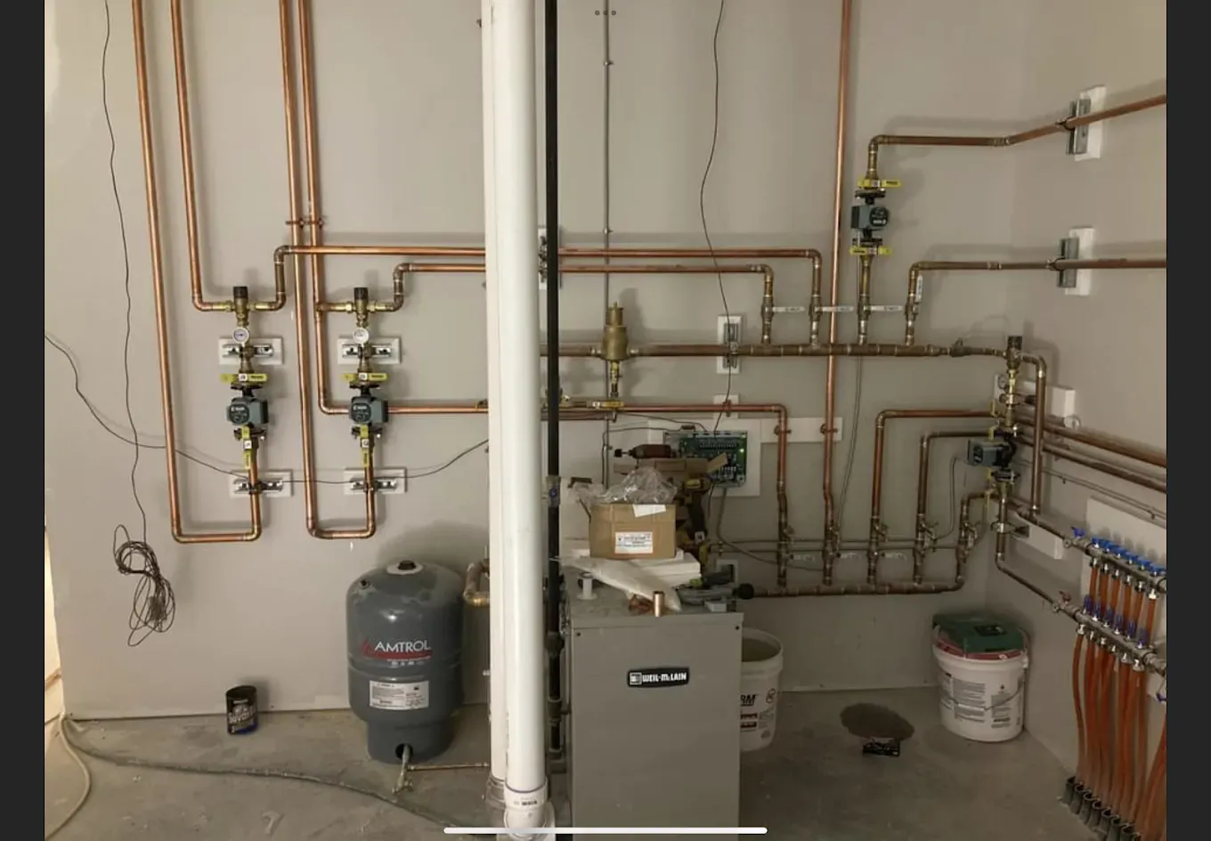 A room with a lot of pipes and a water heater