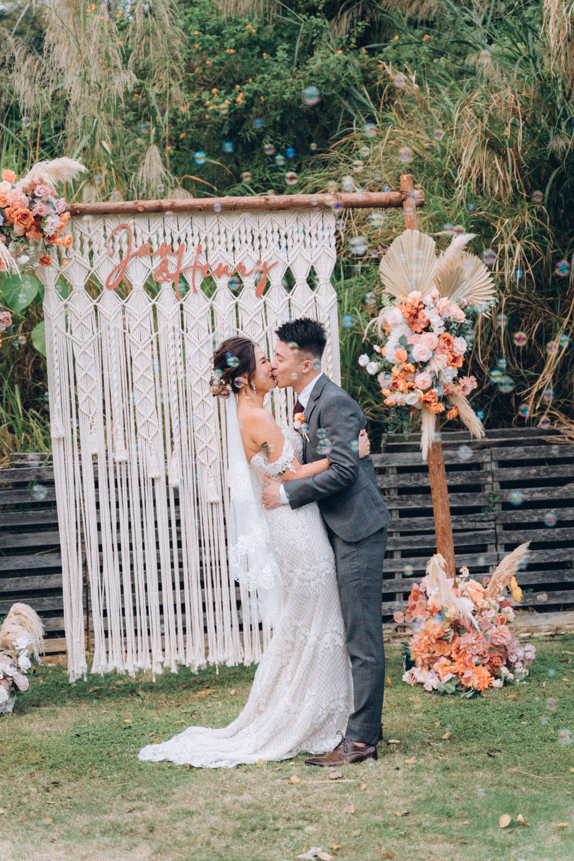 Couple kissing in front of a wedding backdrop. Bubbles float around them.