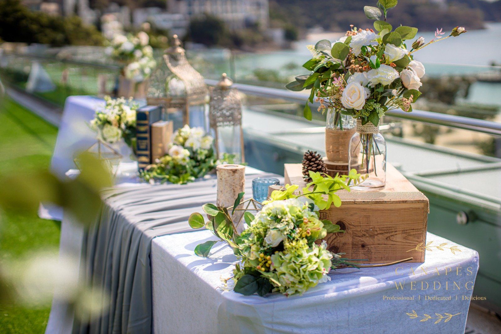 Wedding reception table with floral arrangements, books, candles, and a scenic background.