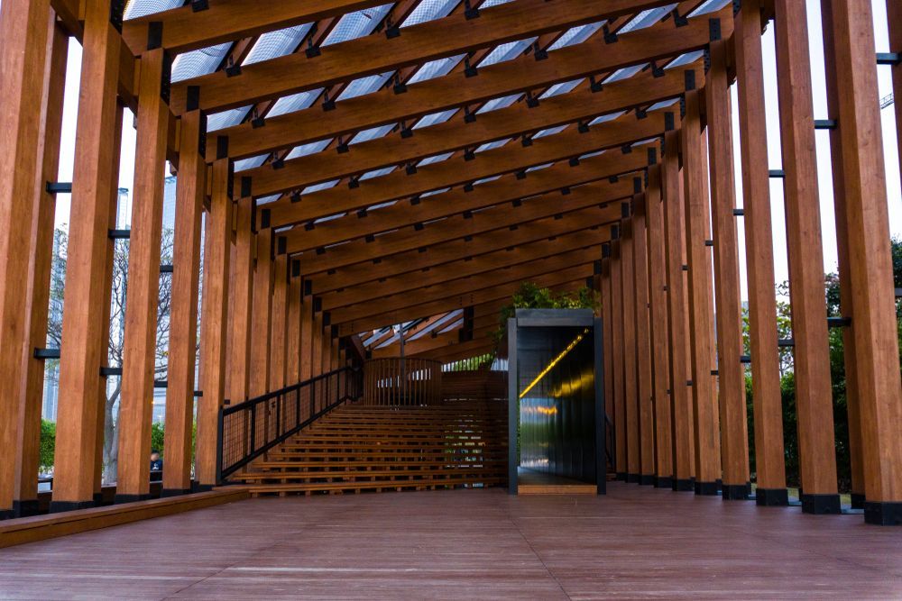 West Kowloon Competition Pavilion, walkway with angled beams, stairs, and a glass display case at the far end