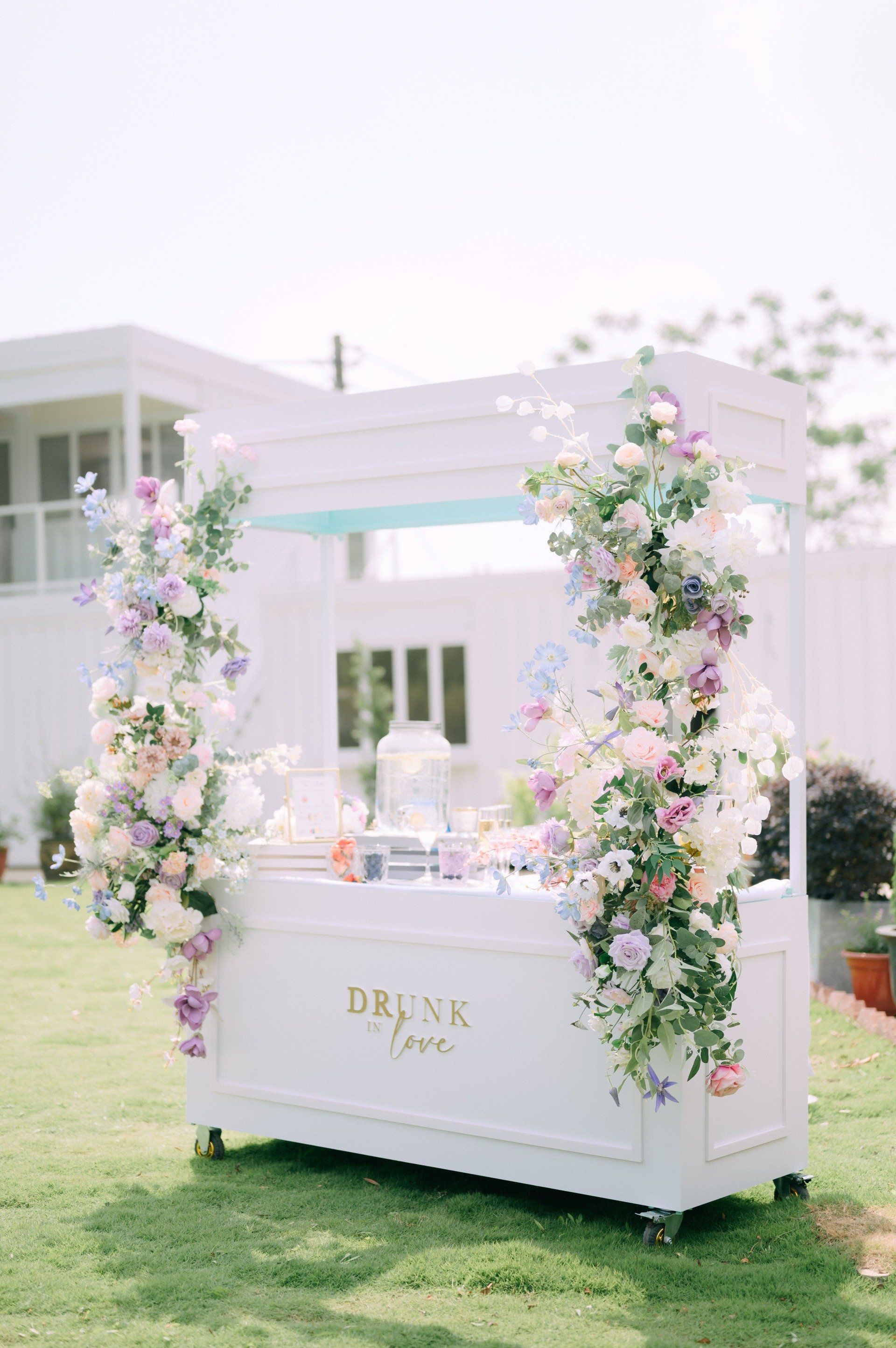White bar decorated with flowers on green grass.
