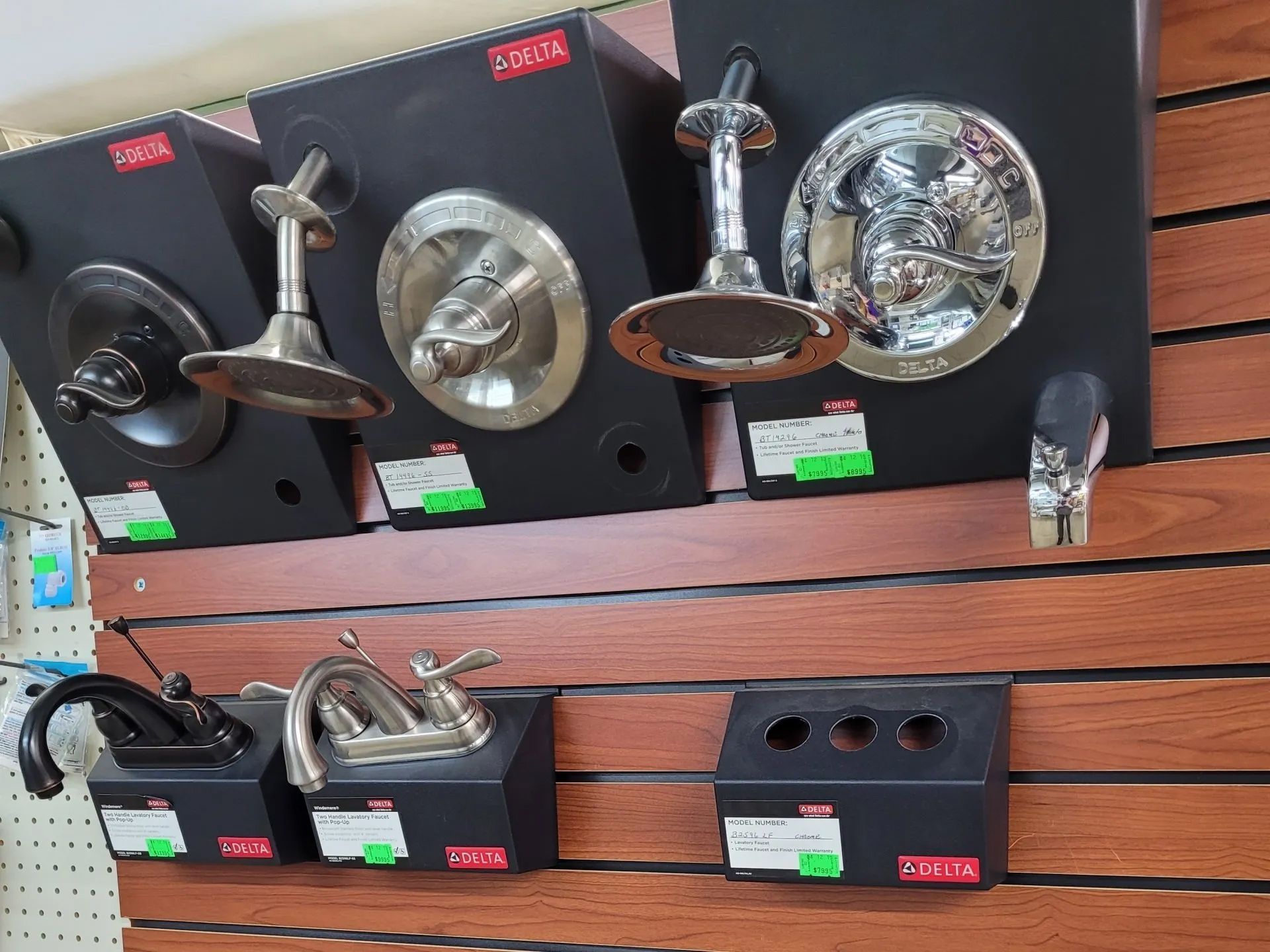 Bunch of Faucets Are Hanging on a Wooden Wall — Hattiesburg, MS — McElhaney Plumbing & Hardware Inc