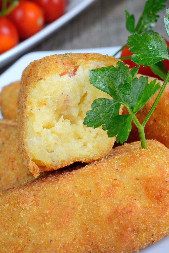 Crocchette dorate e impanate, con ripieno cremoso e guarnite con prezzemolo.