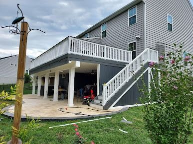 A large house with a large deck and stairs in the backyard.