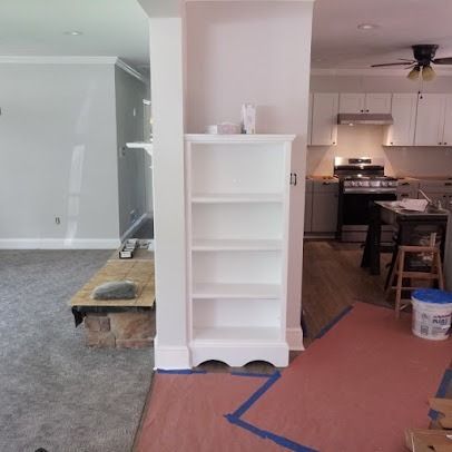 A white bookshelf in a room next to a kitchen