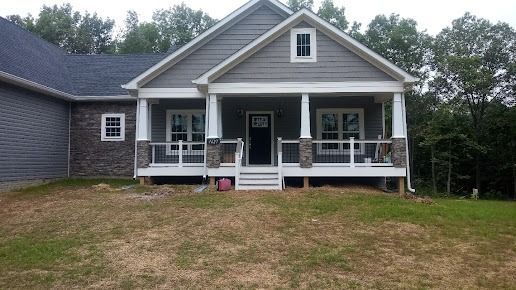 A gray house with a large porch and a white railing.