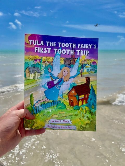 A hand holds a children's book titled 