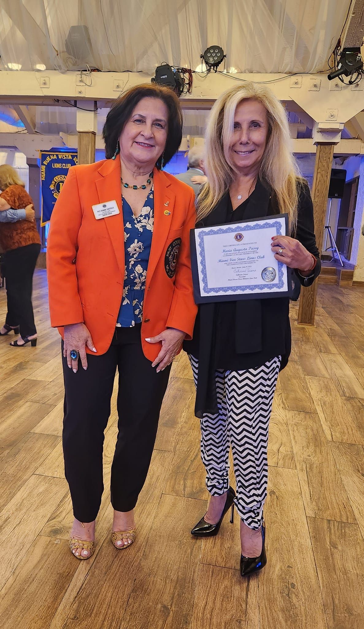 Two women are standing next to each other in a room holding a certificate.