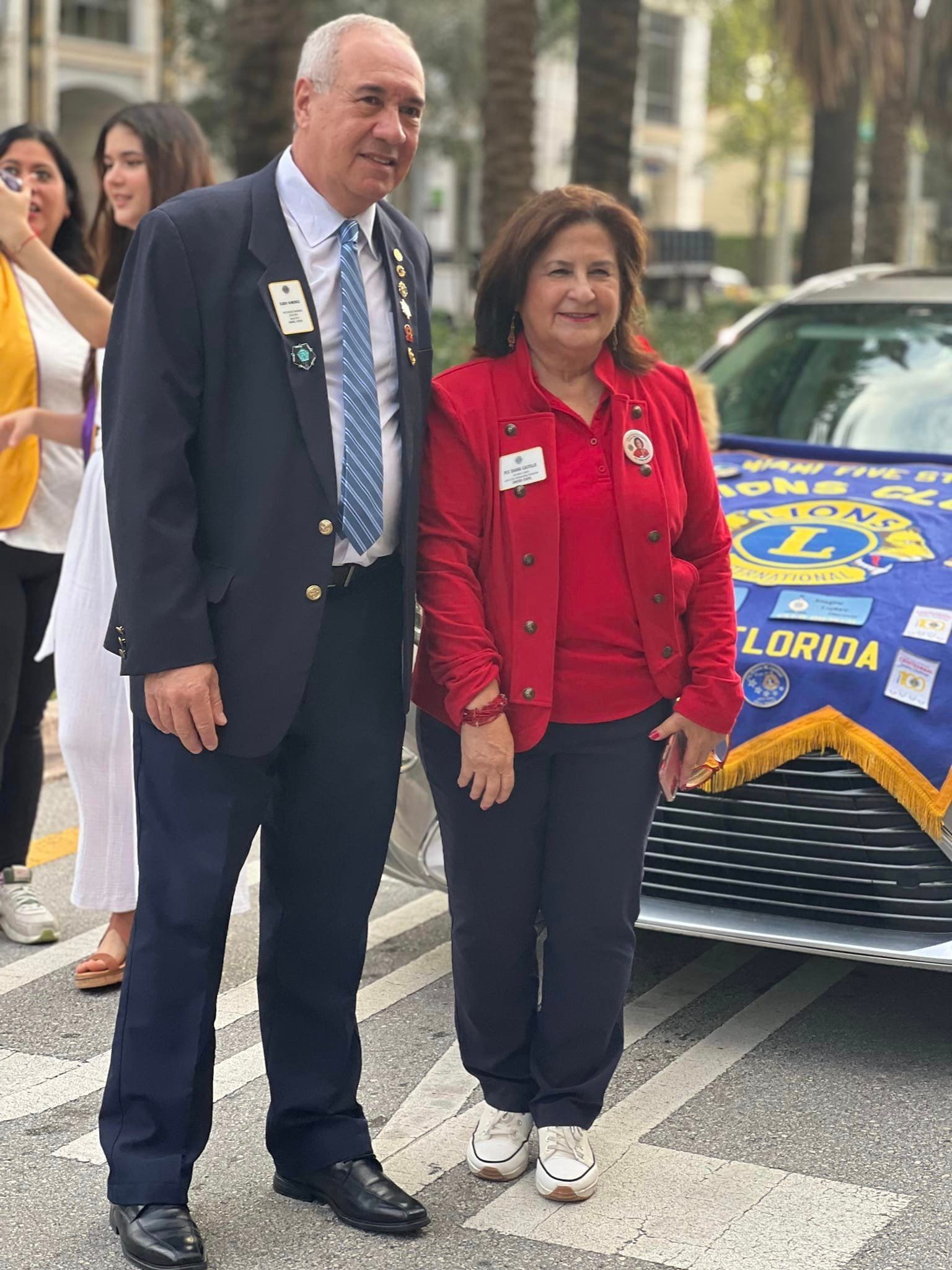 A man and a woman are standing next to each other in front of a car.