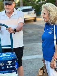 A man is pushing a dolly with a stack of boxes on it.