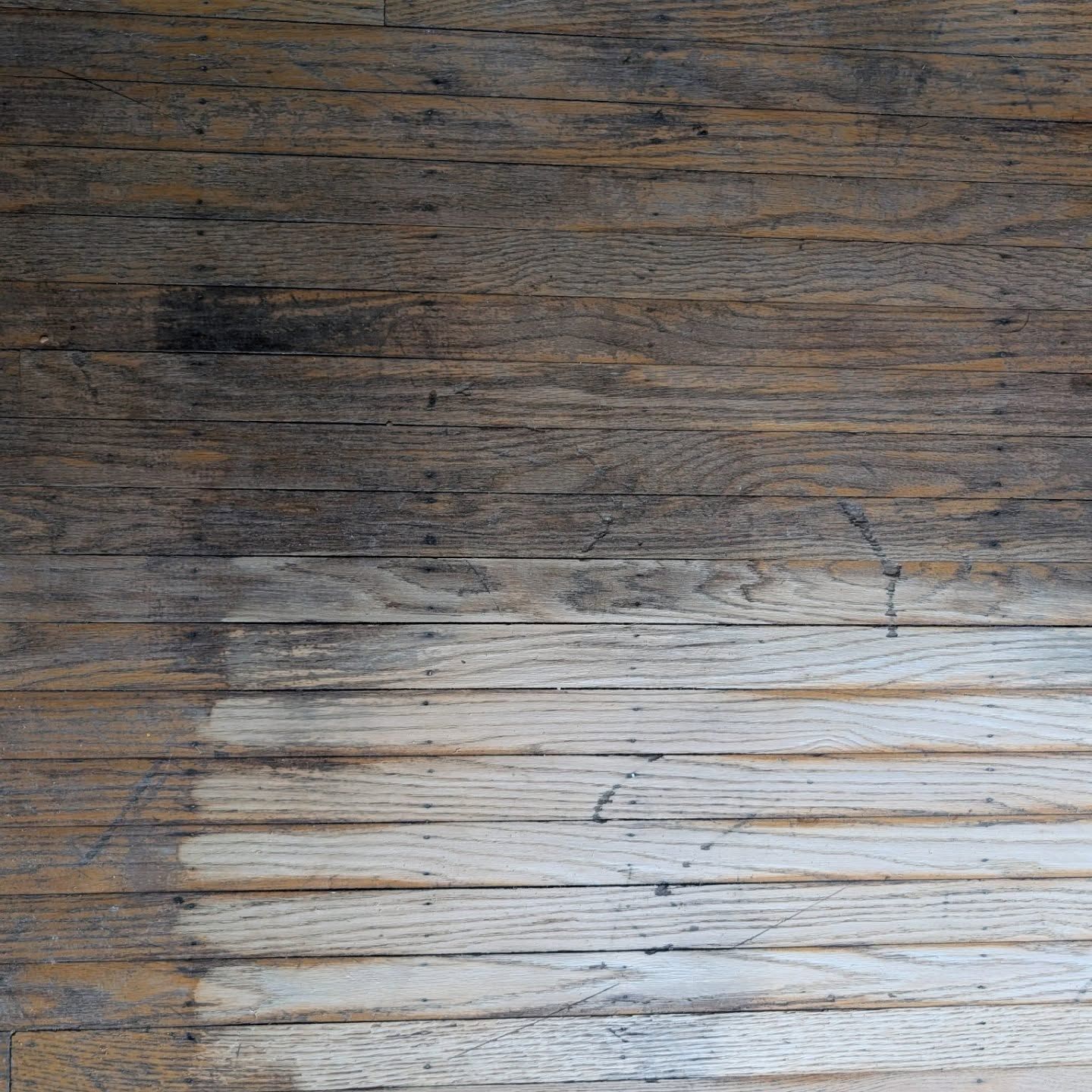 Weathered wooden surface with a dark upper half and a lighter worn area below.