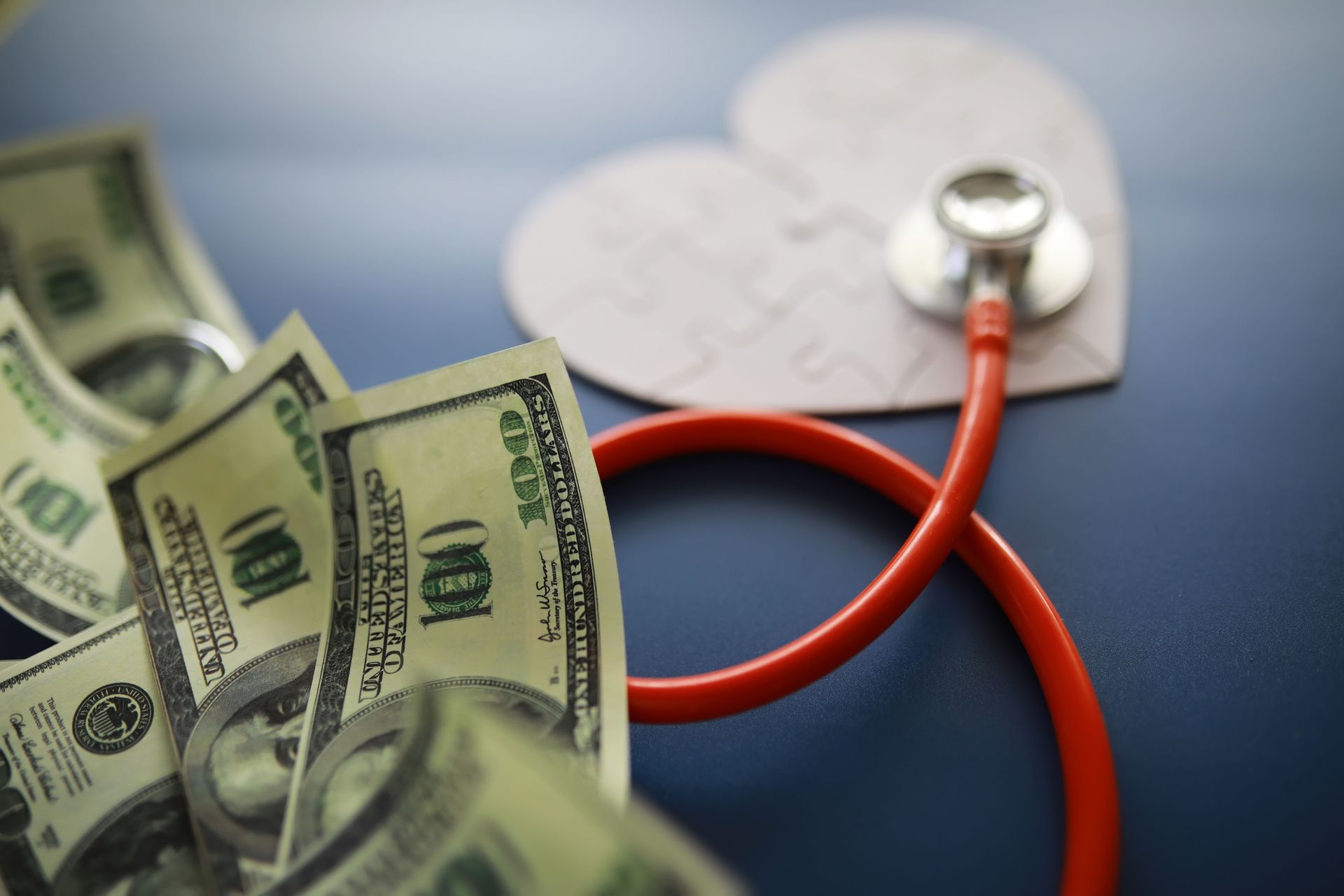 A stethoscope is laying on top of a heart made out of money