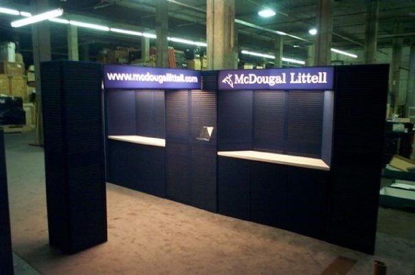 Empty McDougall Littell booth with dark blue walls and illuminated signage in a trade show hall