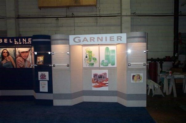 Garnier trade show booth with product displays and posters in a dim exhibition hall