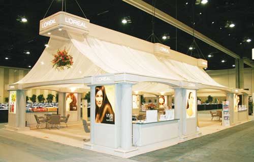 L'Oréal trade show booth with white canopy, advertisements, and displays.