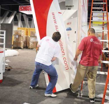 Two people moving a white and red panel with 