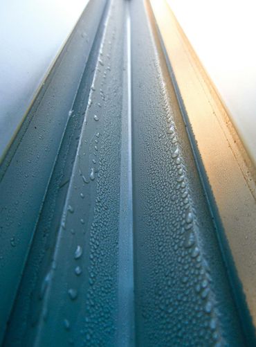Close-up of a blue frosted glass panel with water droplets and warm light along the edge