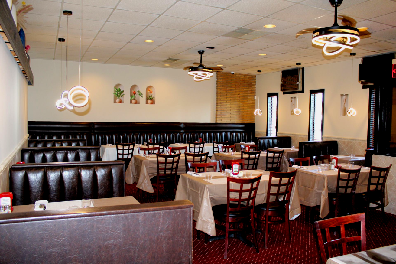 Restaurant interior with booths, tables, chairs, and decorative lighting.