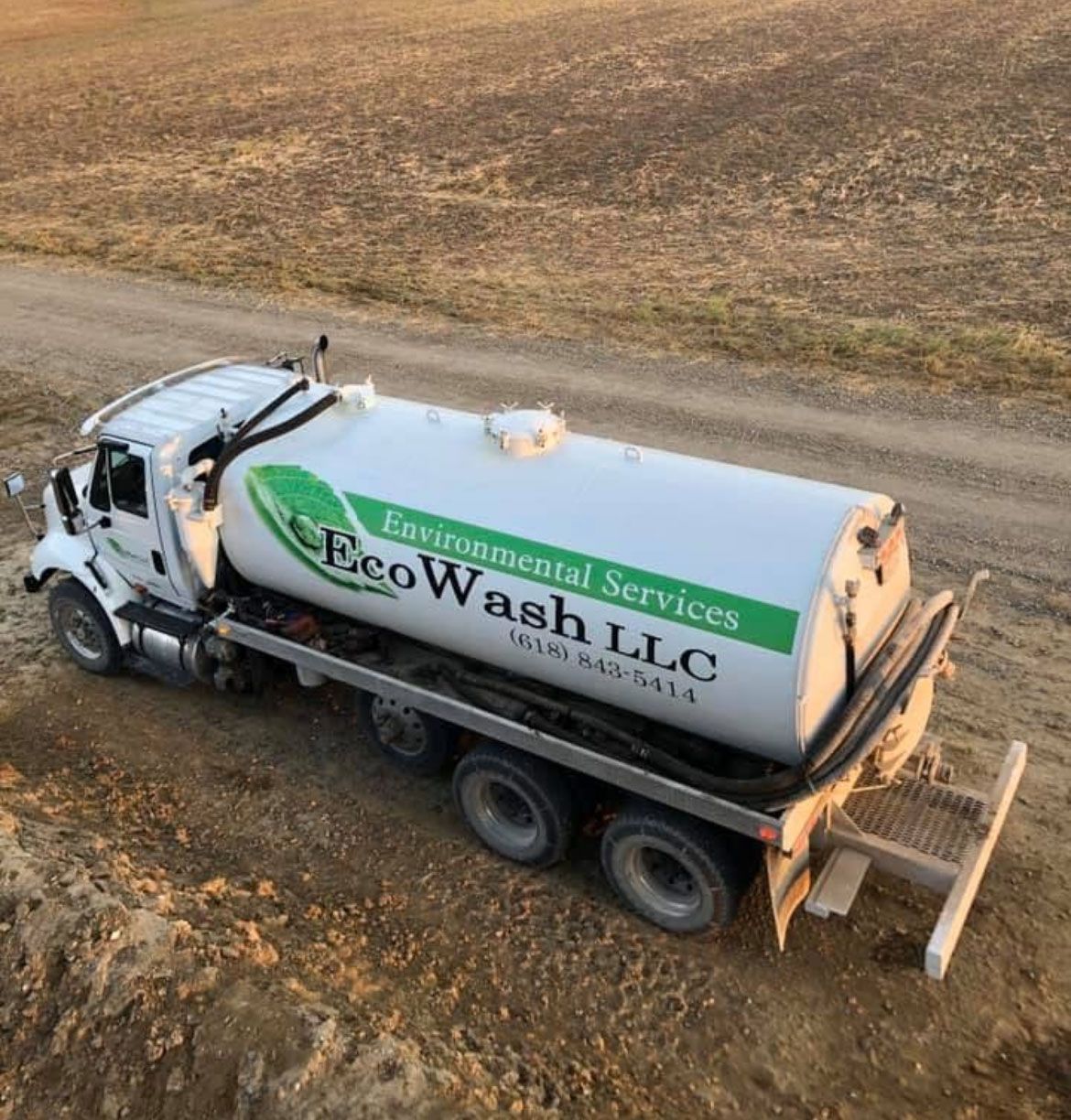 White EcoWash LLC truck on a dirt road in a field.