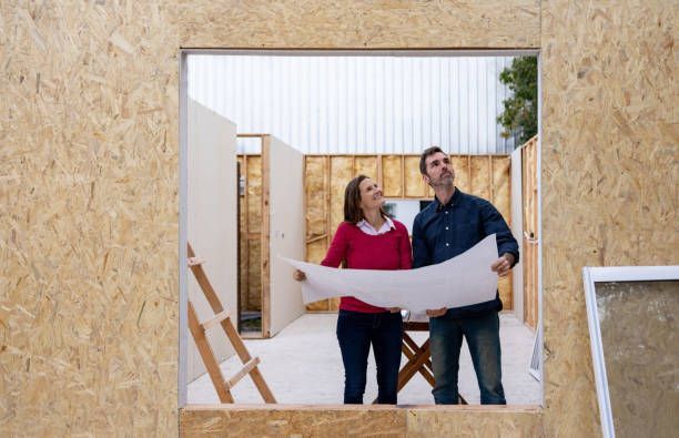 A couple stands in a room with a blueprint, representing a Custom Home Builder in Hamilton, OH, planning their new home.