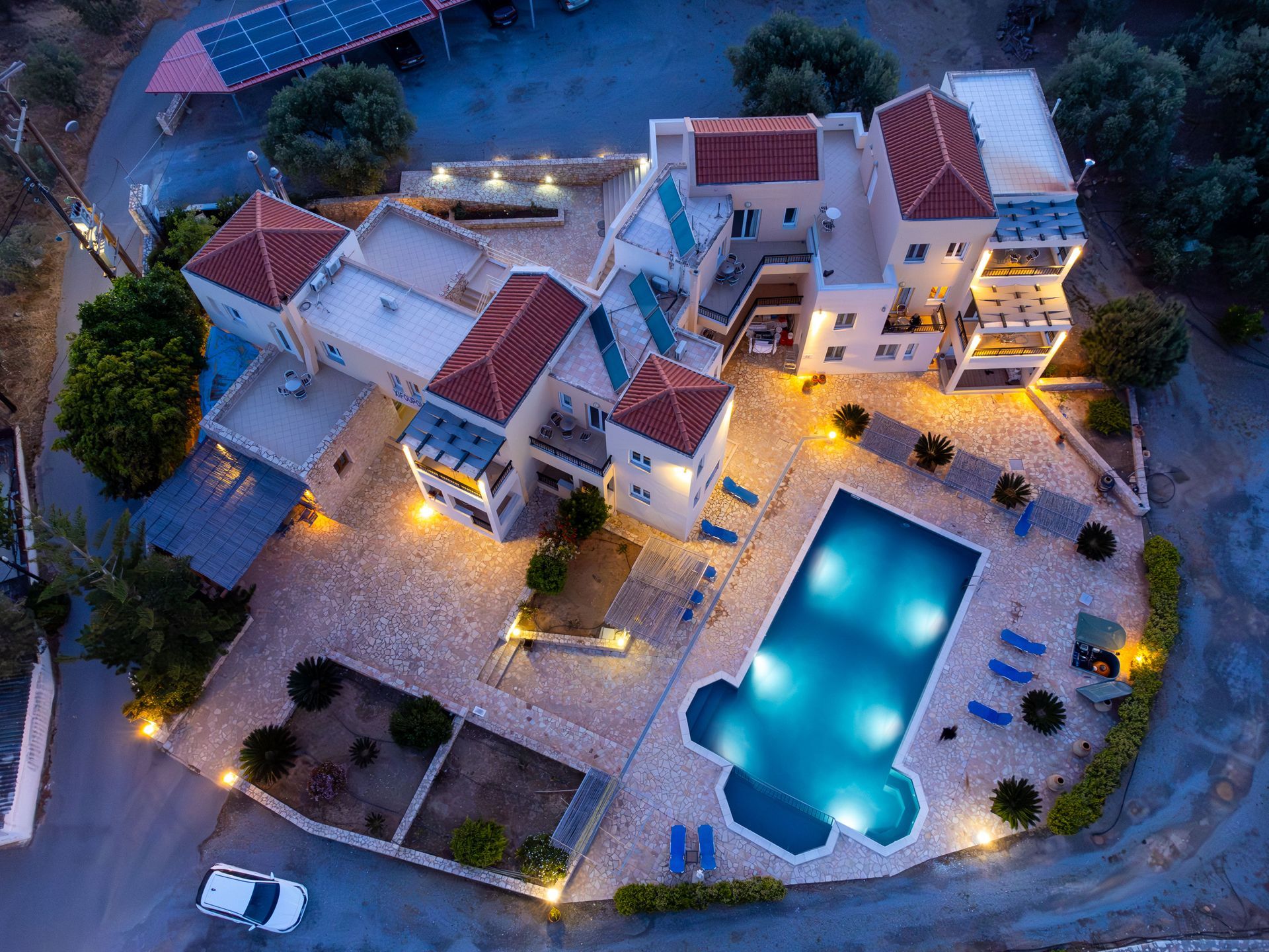 Whitewashed buildings with blue doors and shutters line a cobblestone street under a bright blue sky.
