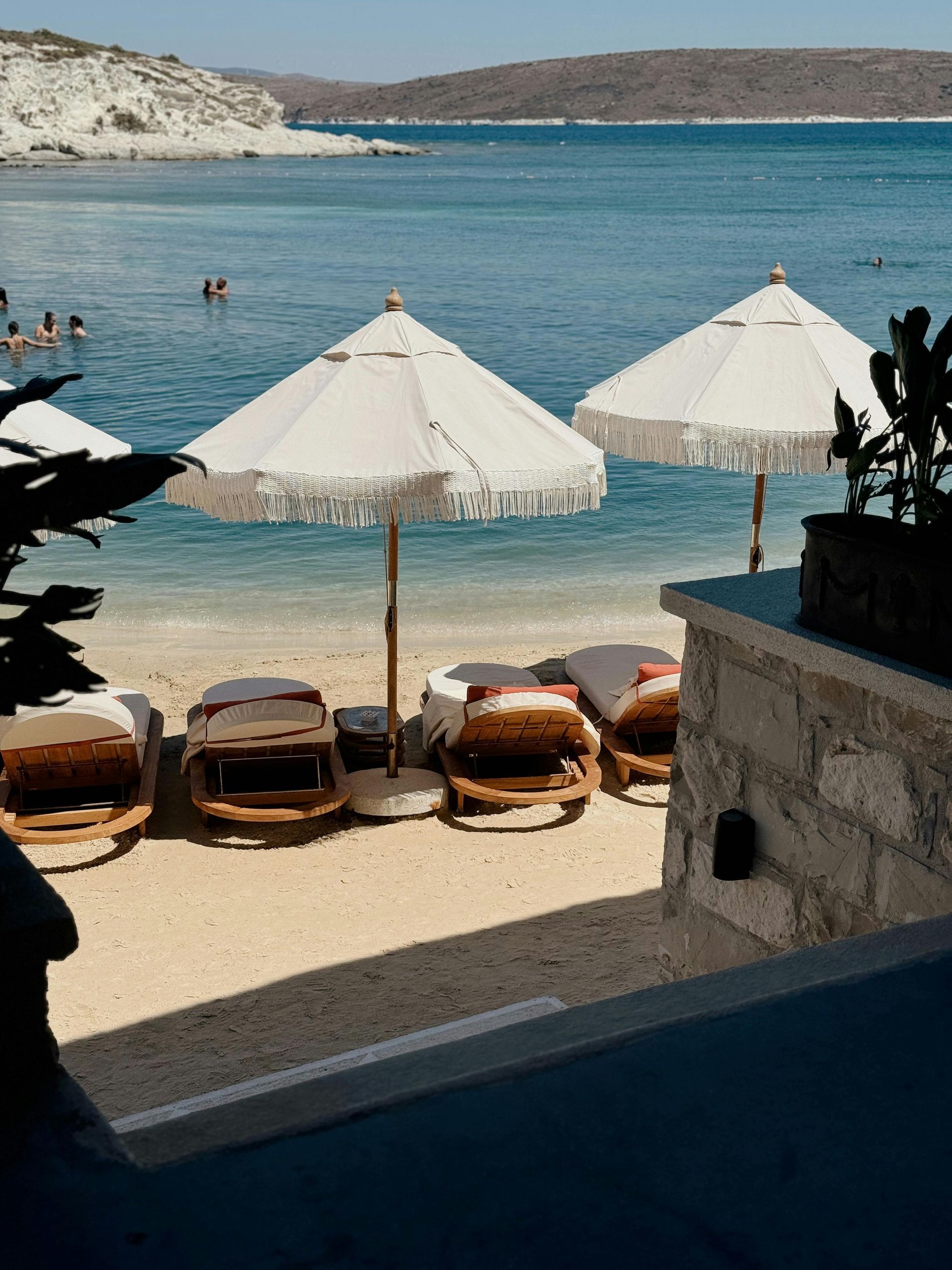 Beach scene with white umbrellas, lounge chairs, and calm turquoise water.