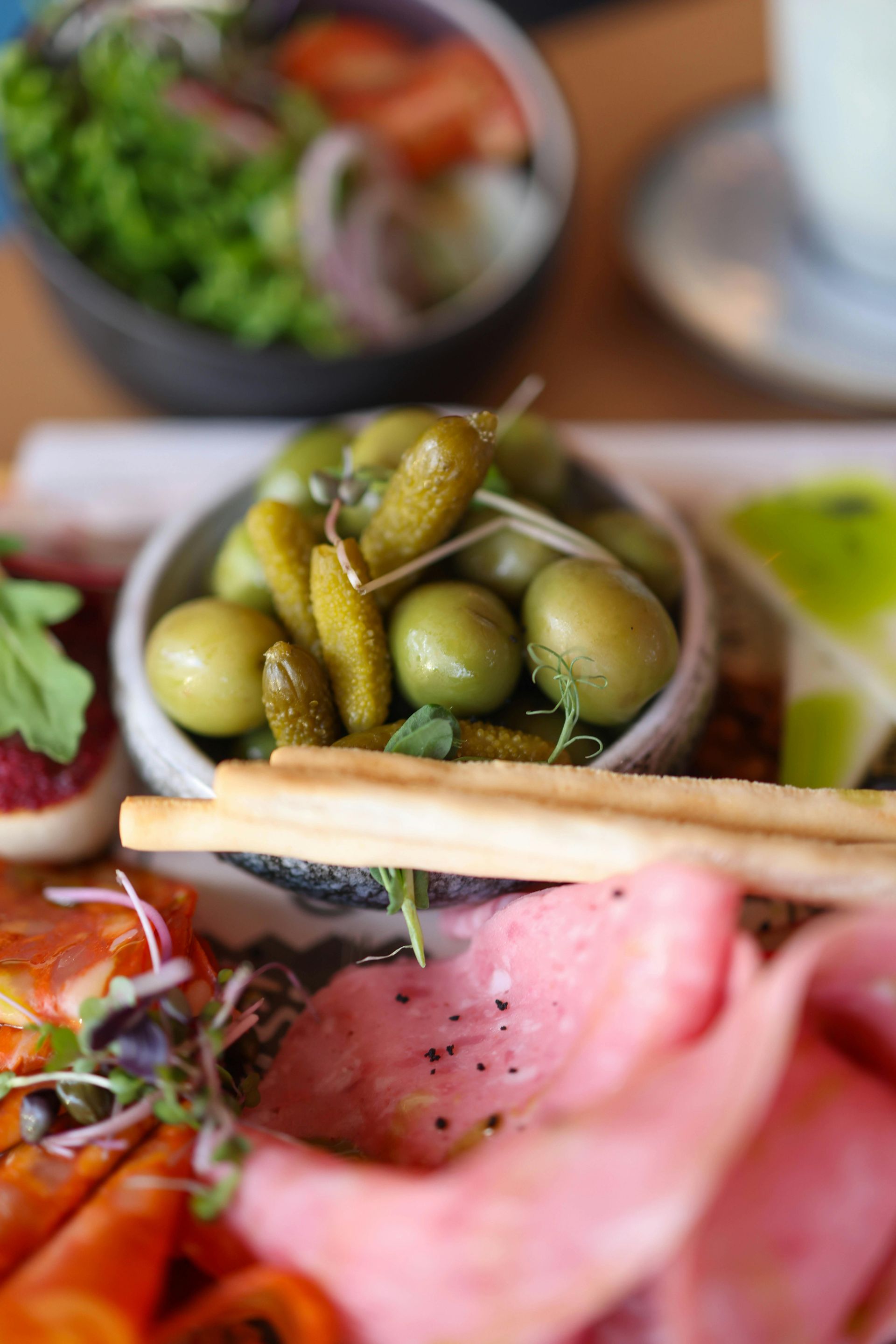 Charcuterie board: olives, pickles, breadsticks, meats, salad, and appetizers.