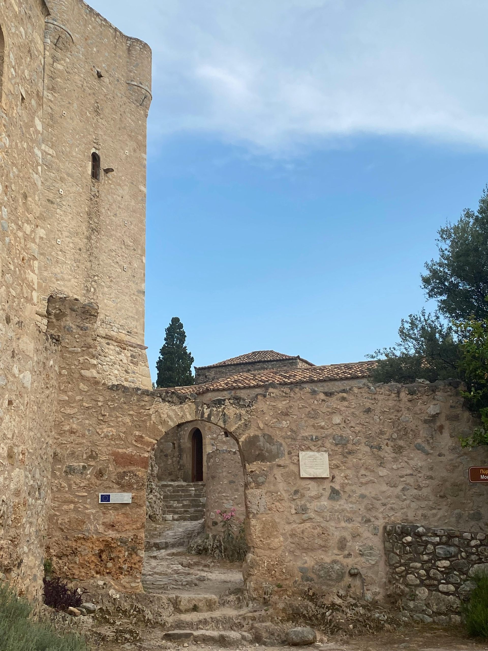Stone castle ruins, arched doorways, steps, and clear blue sky.