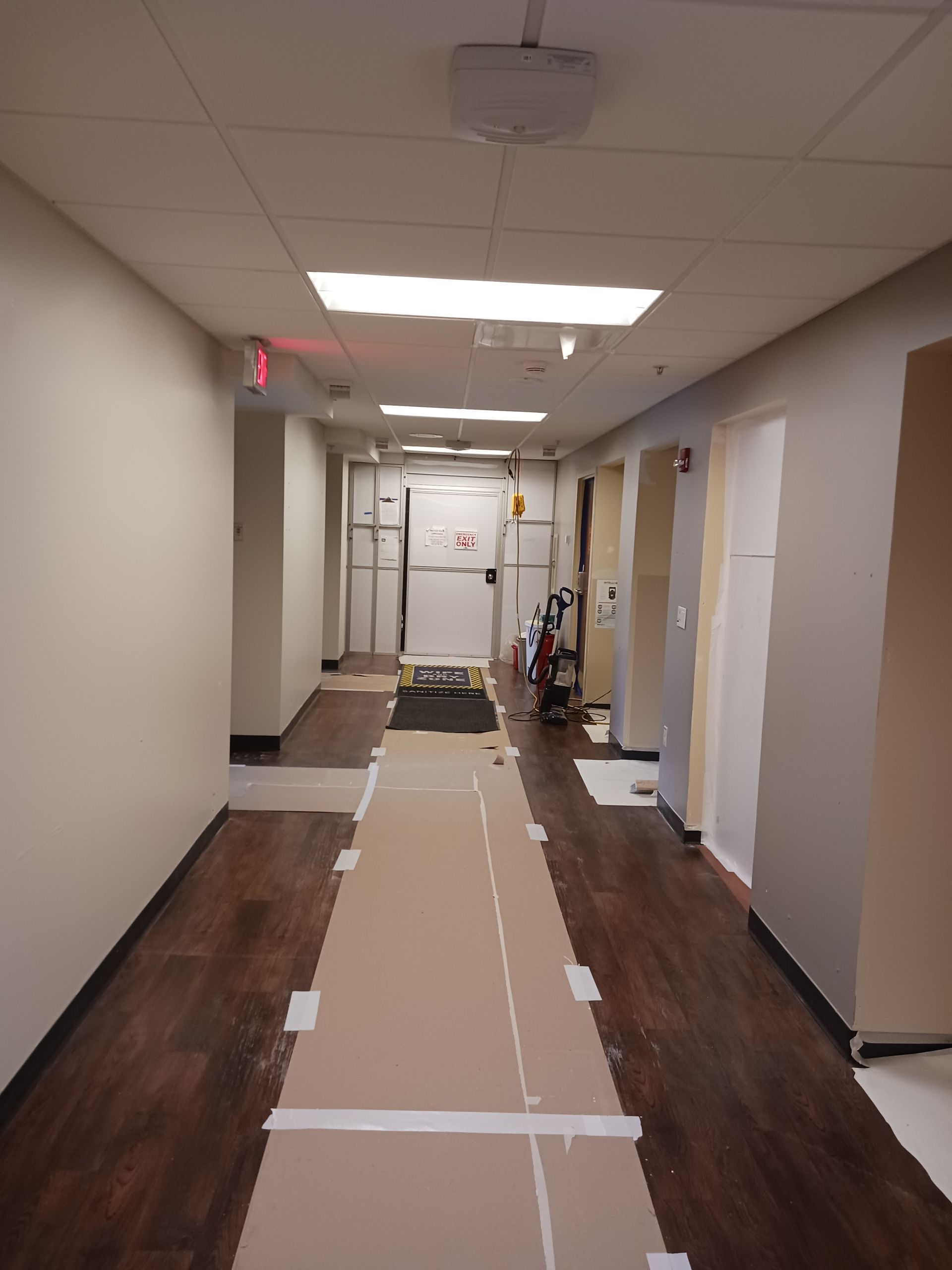 A long hallway with a red exit sign at the end