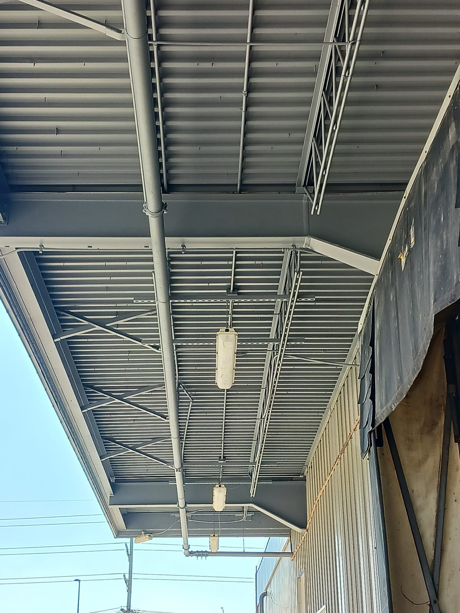 The ceiling of a building with a lot of pipes hanging from it.