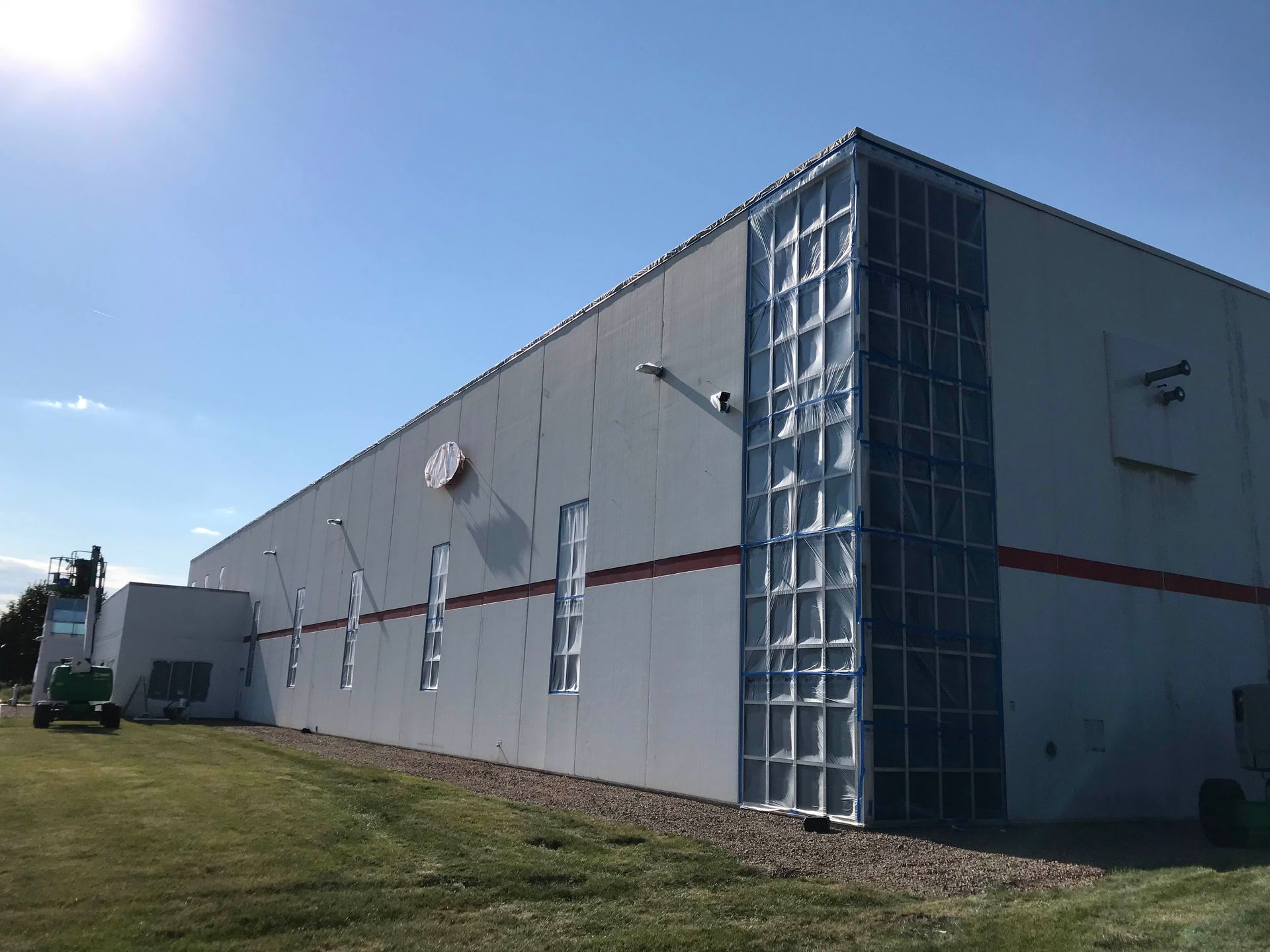 A large white building with a lot of windows is sitting on top of a lush green field.