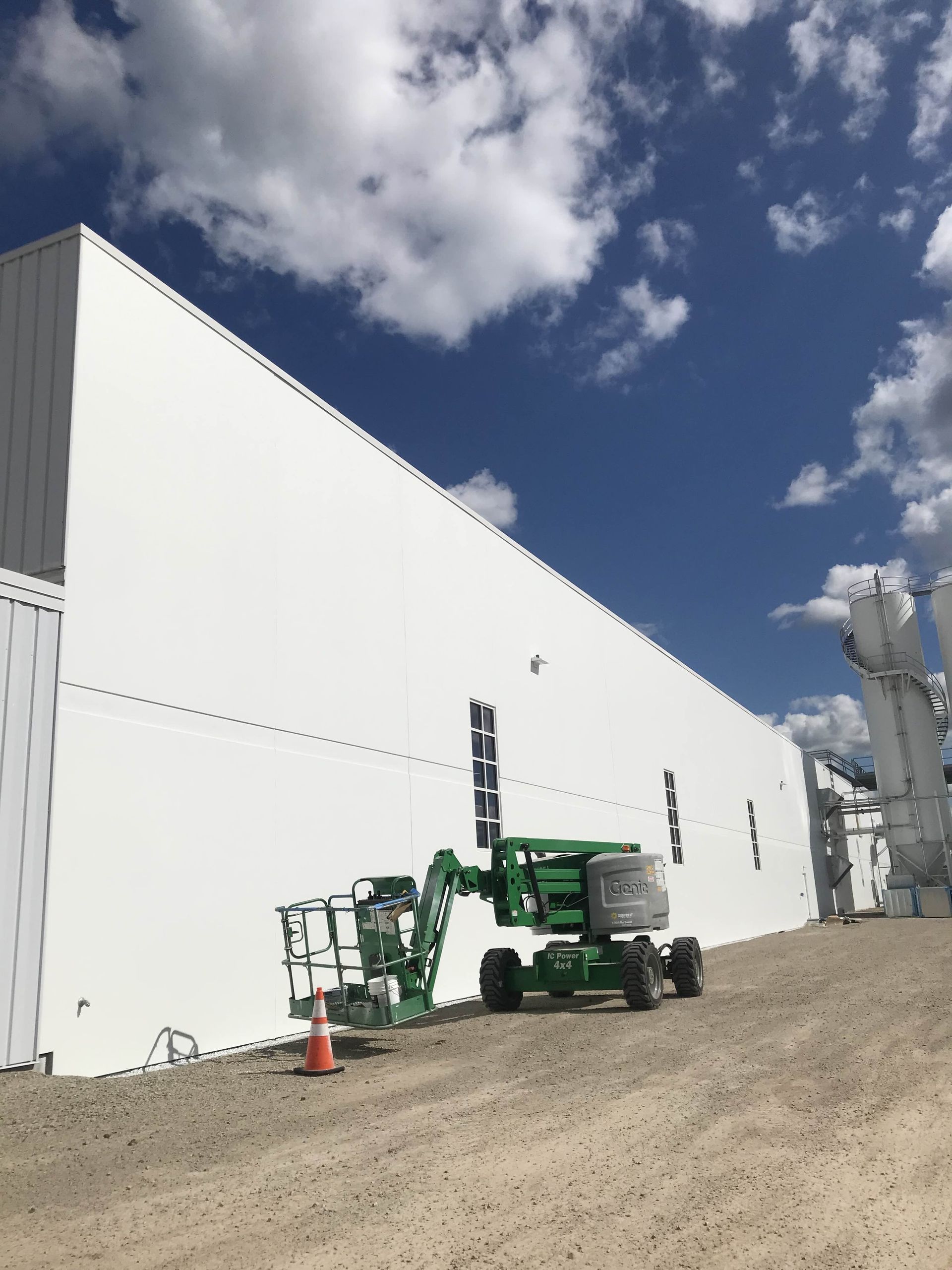 A green lift is parked in front of a white building