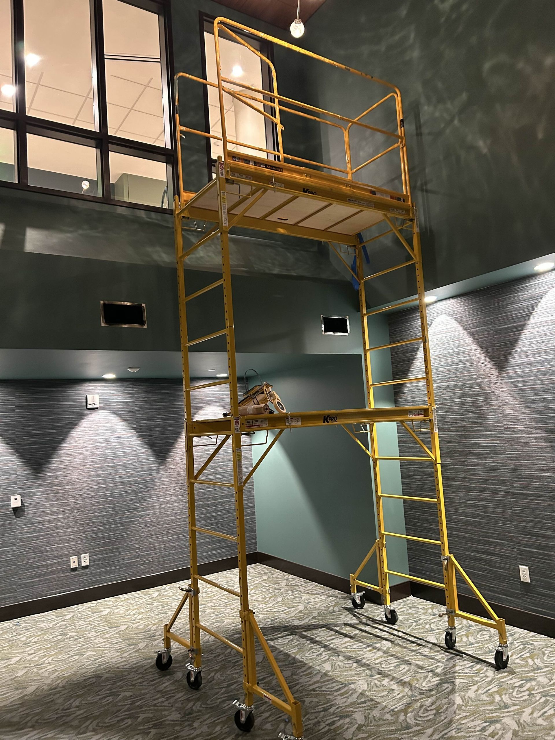 A yellow scaffolding with wheels is sitting in a room.