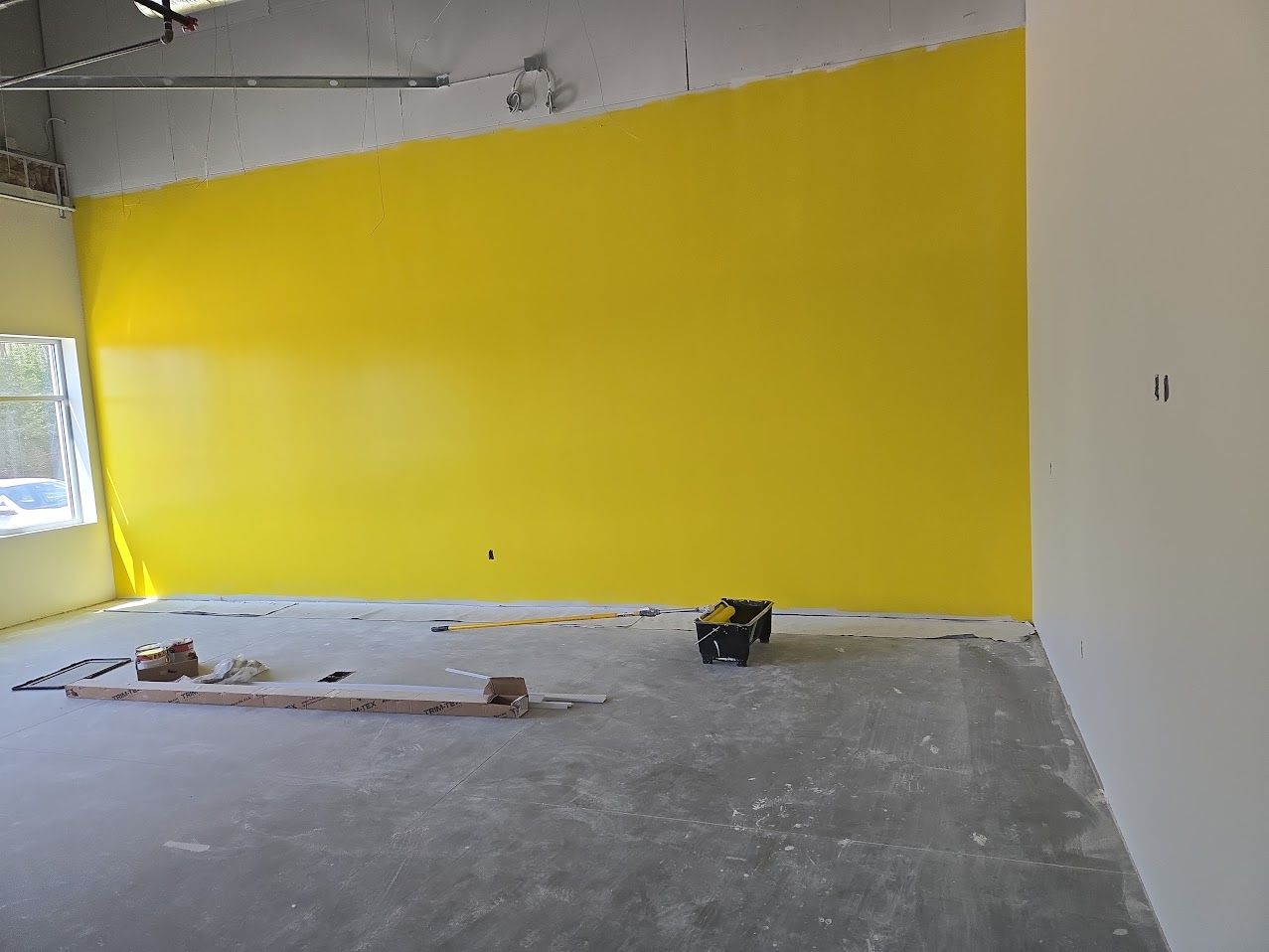 An empty room with a yellow wall and white walls