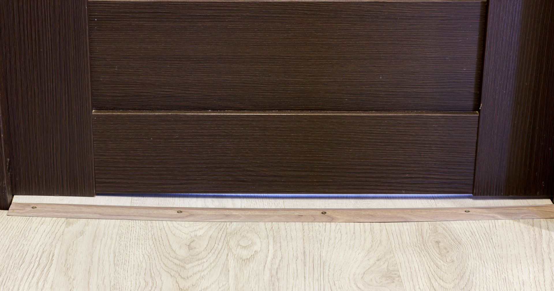 Dark brown door with light wood flooring and a wooden threshold. Dark brown door with light wood flooring and a wooden threshold.