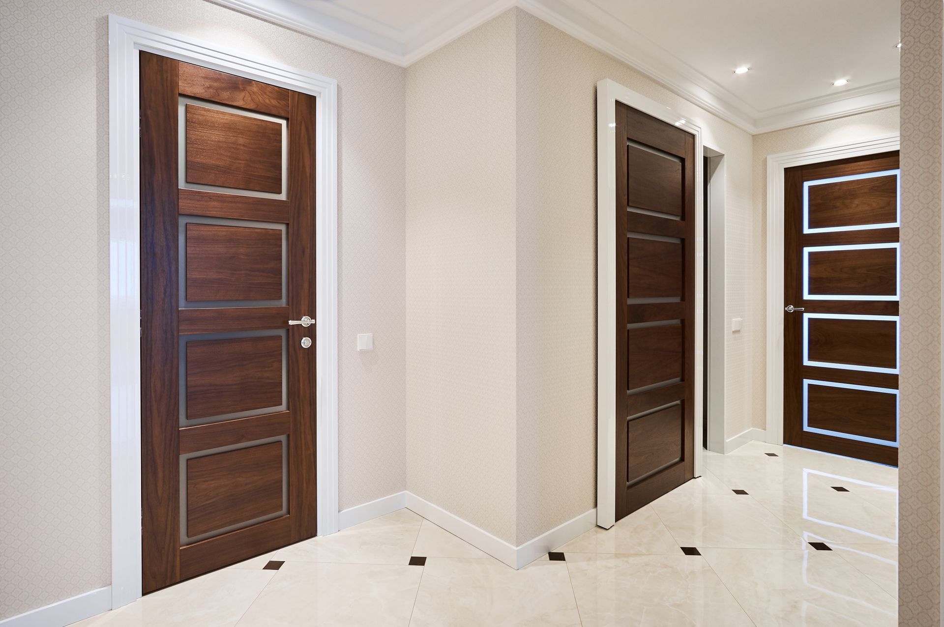Hallway with three dark wood doors, white trim, and light beige walls.