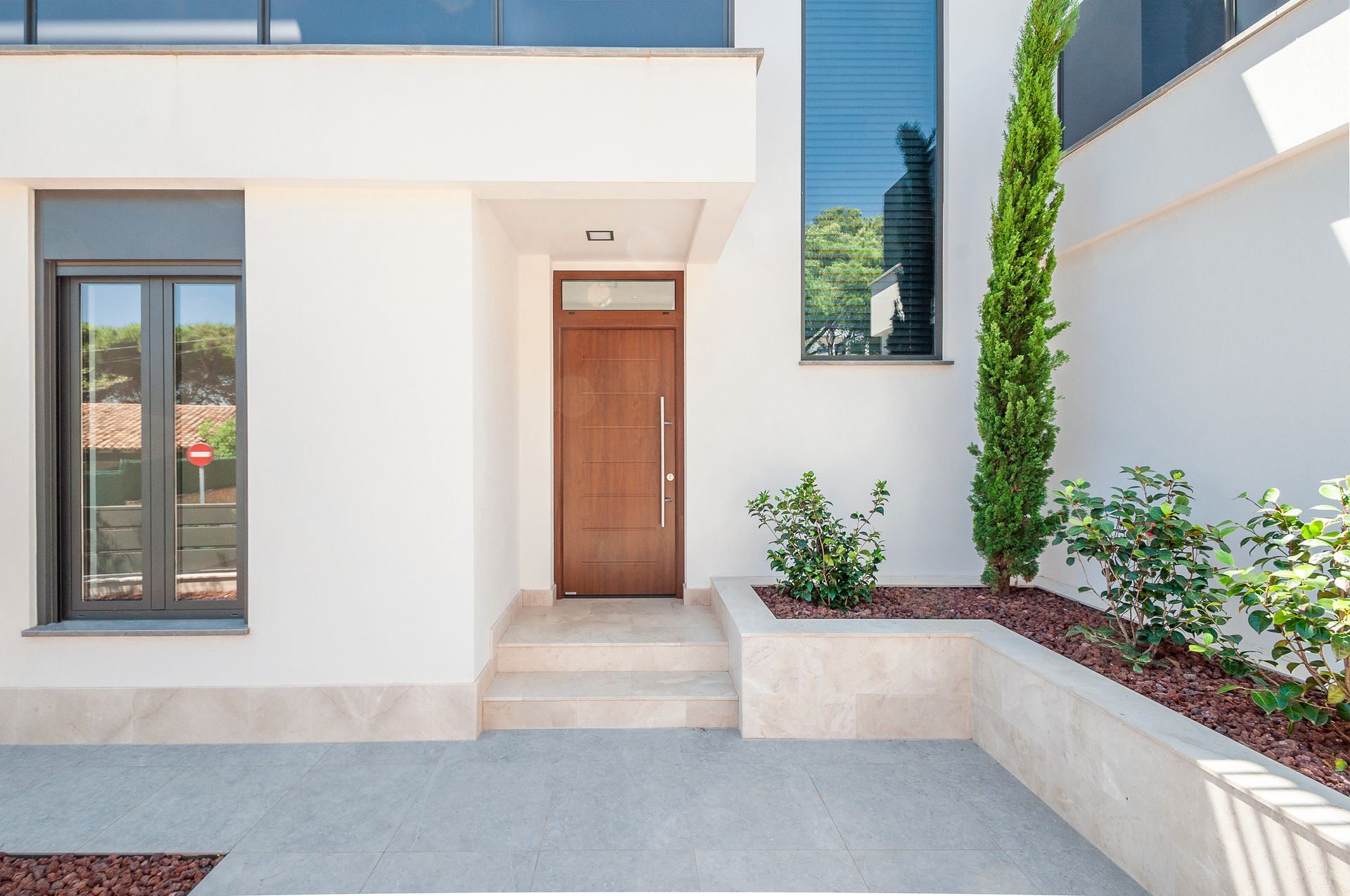 Modern white building entrance with brown door and small front garden. Modern white building entrance with brown door and small front garden.