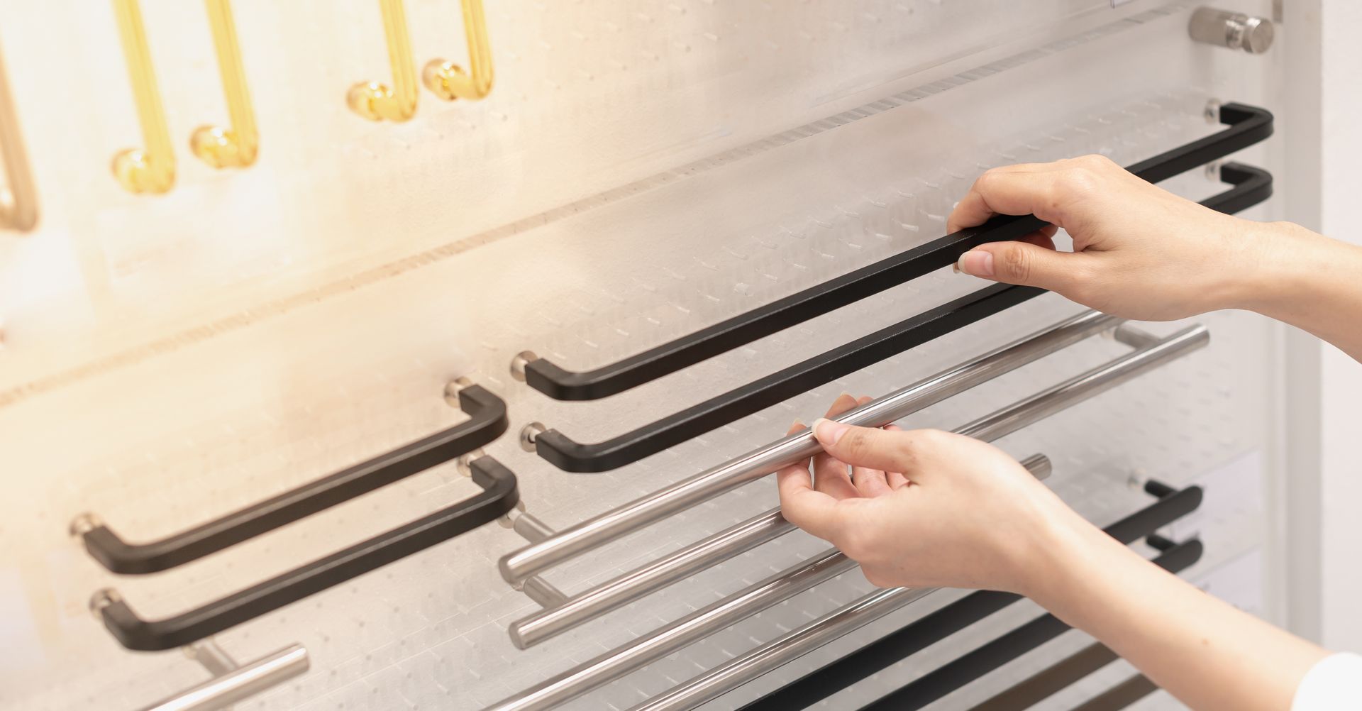 Hands selecting a metal door handle from a display rack in a hardware store. Hands selecting a metal door handle from a display rack in a hardware store.