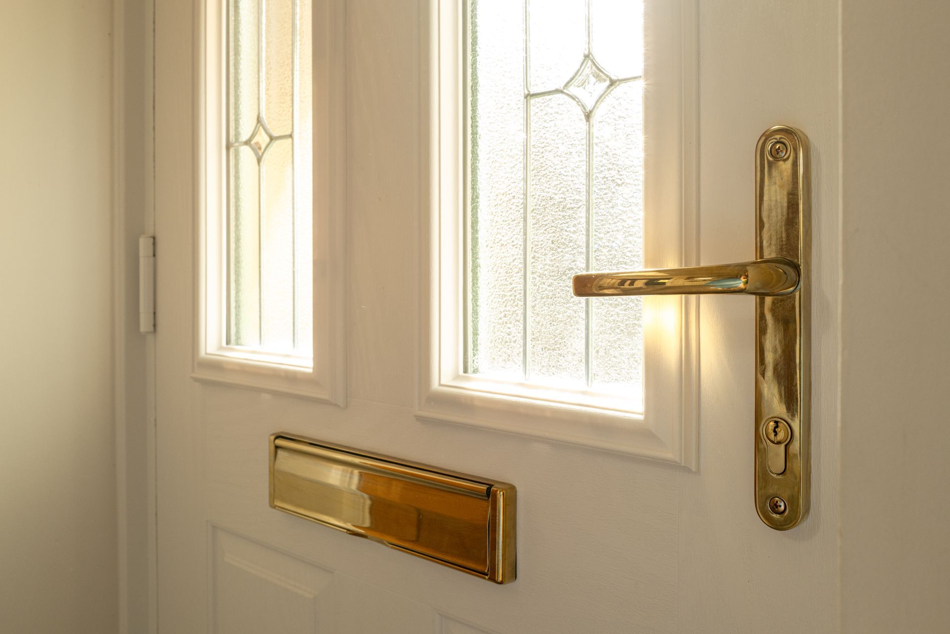 White front door with brass handle, mailbox, and frosted glass windows. White front door with brass handle, mailbox, and frosted glass windows.