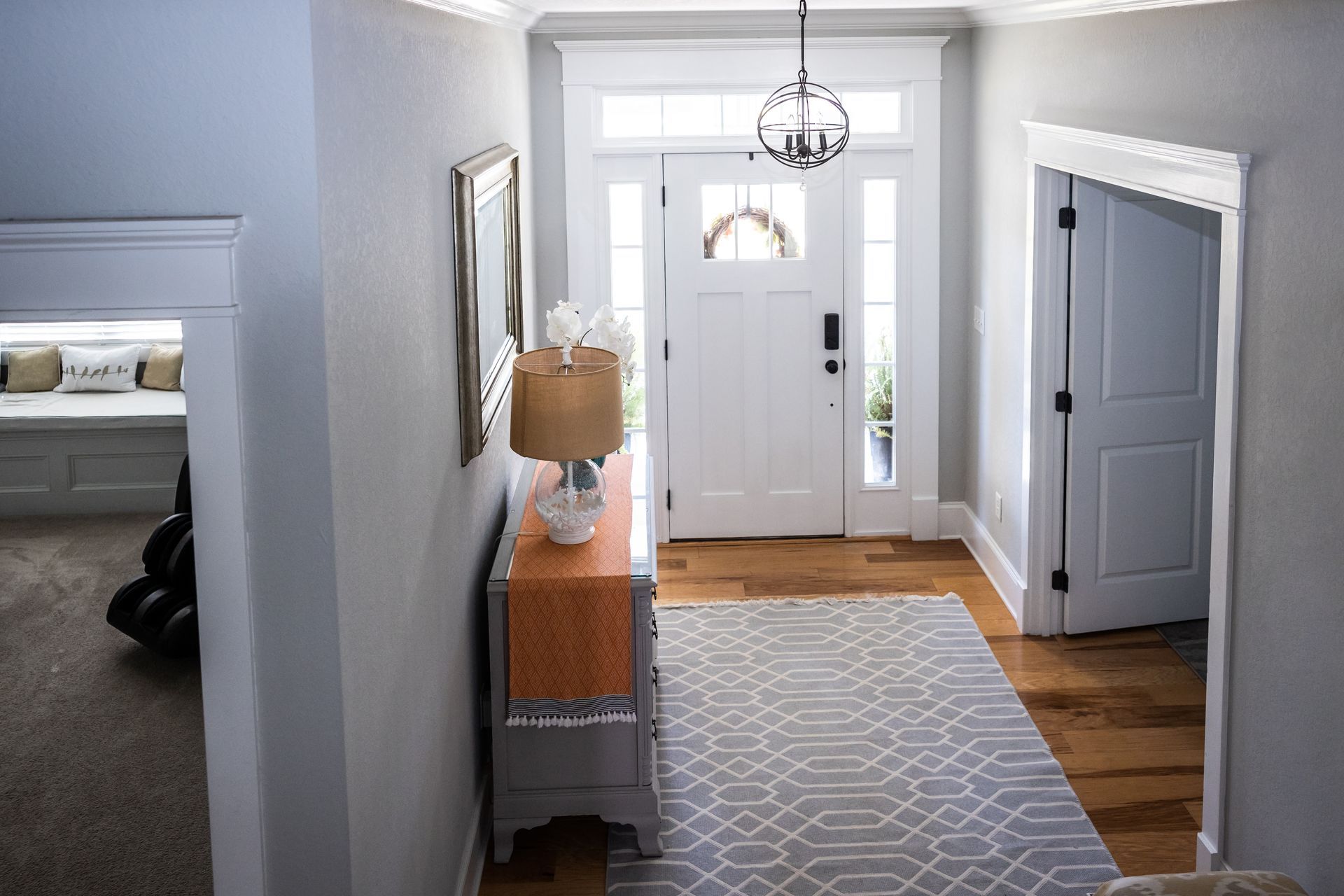 Entryway with gray walls, wooden floors, white door, and a gray patterned rug.