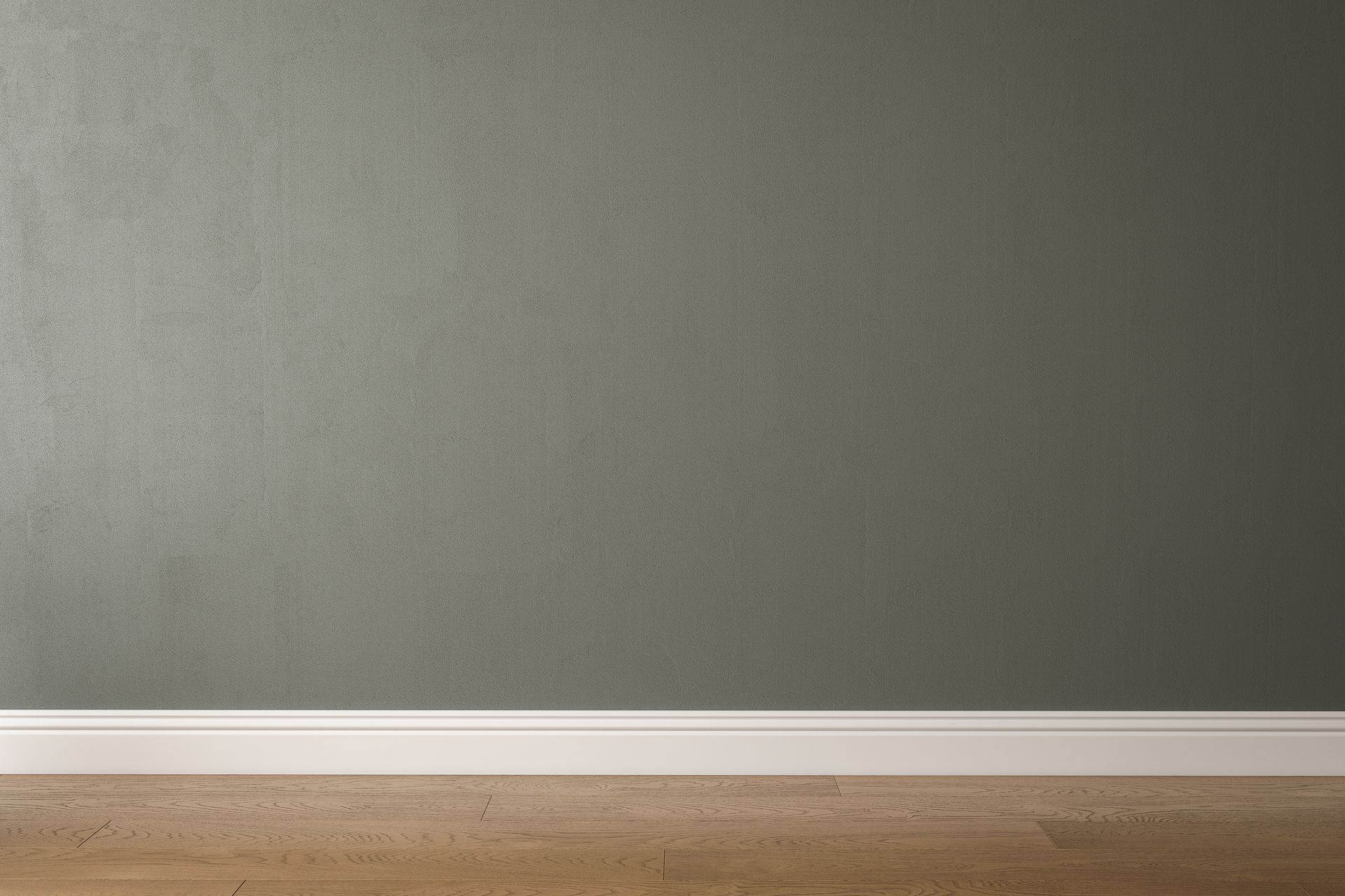 Gray wall with white baseboard and wooden floor.