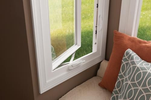 White casement window open, revealing green lawn. Pillows on window seat. White casement window open, revealing green lawn. Pillows on window seat.