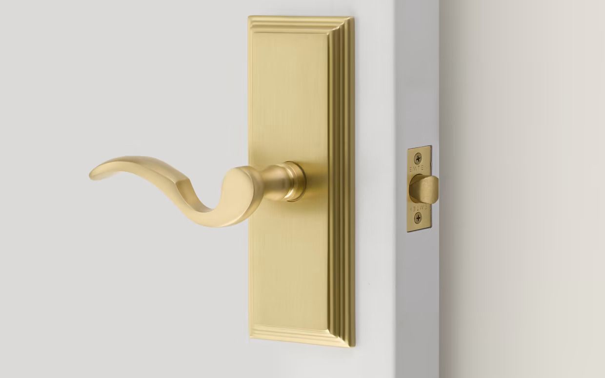 Brass door handle and latch on a white door. Brass door handle and latch on a white door.