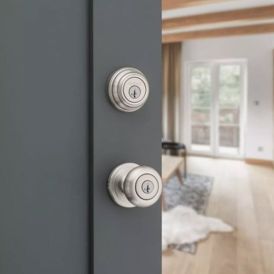 Gray door with a deadbolt and doorknob in a brushed nickel finish, leading into a bright interior. Gray door with a deadbolt and doorknob in a brushed nickel finish, leading into a bright interior.